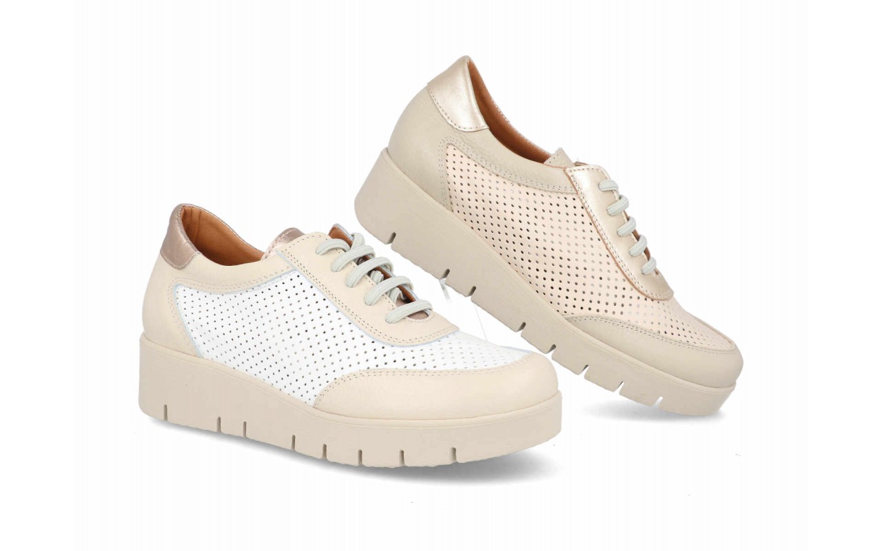 Zapato deportivo de piel para mujer modelo 125 con paneles laterales calados, detalles en el talón de piel metalizada, cordones elásticos y suela de plataforma con relieves.